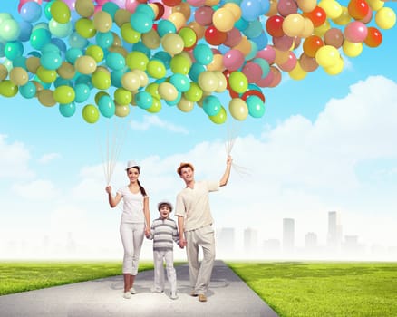 Happy young family walking holding bunch of colorful balloons