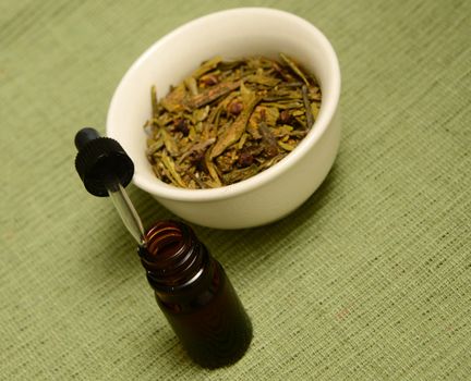 essential oil with herbs on green background