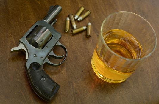 deadly combination of alcohol and firearms on wood background