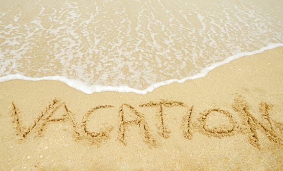 A warm tropical beach with waves and vacation written in the sand 