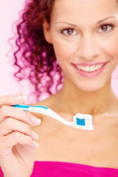 portrait of a smiling woman and teeth brush, focus on brush