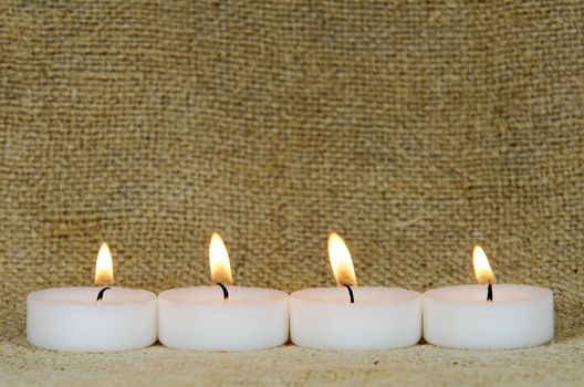 four candles on burlap background