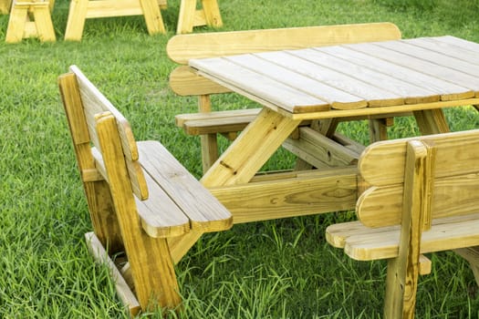 A side view of a wooden picnic table set around bright green grass.