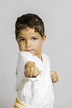A small boy punching wile dressed in karate uniform.
