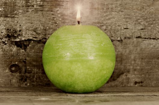 green candle on wooden background