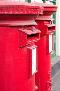 Closeup of two traditional British red mail boxes.