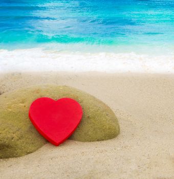 Red Heart shape on the sandy beach by the ocean