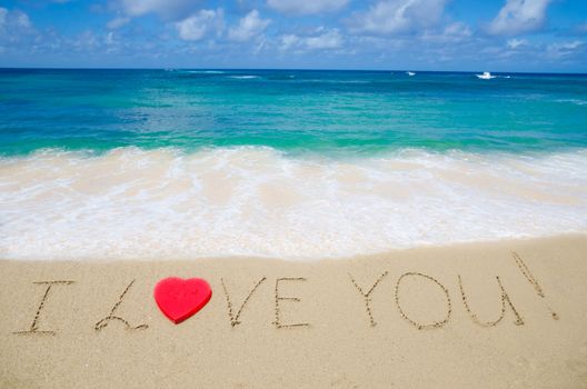 Sign "I Love You" with red heart shape on the beach