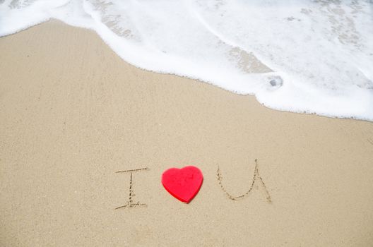 Sign "I Love You" with red heart shape on the beach