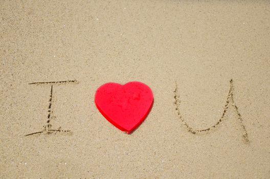 Sign "I Love You" with red heart shape on the beach