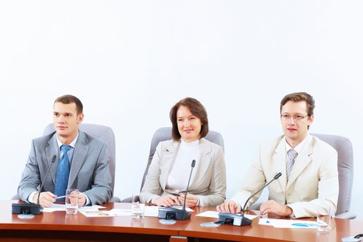 Image of three businesspeople sitting at table at conference