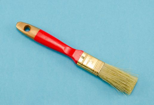 brush 25mm 1" wide with a red shaft handle on blue background. paint tool.