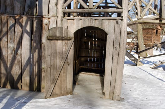 wooden playground house door covered with ice and snow in winter.