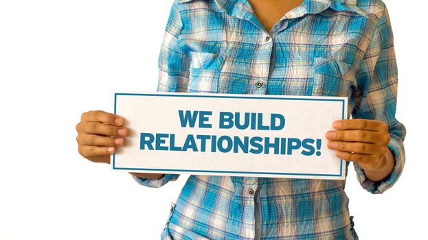 A woman holding a We Build Realationships sign.