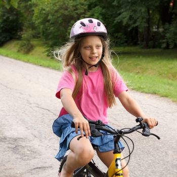 smiling little girl rides a bicycle
