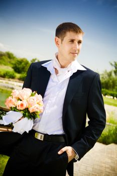 well-dressed groom with rose bouquet