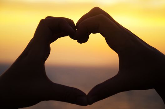 Silhouette of hand in heart shape on sunset in Malibu
