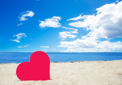 Red heart shape on sandy beach by the ocean