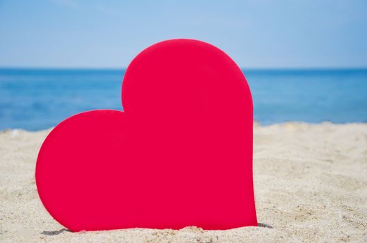 Big red Heart shape on sandy beach by the ocean