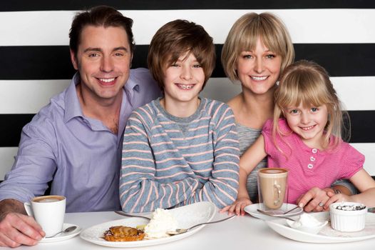 Cheerful caucasian family of four having fun in restaurant.