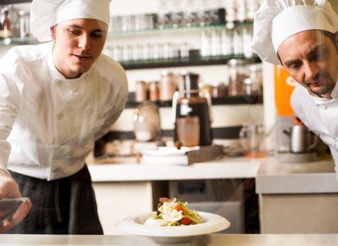 Two professional male chefs in restaurant kitchen.