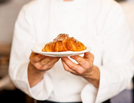 Cropped image of make chef holding fresh and tasty roll croissants.