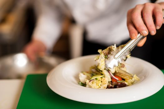 Closeup image of a salad ready to be served being decorated by chef.