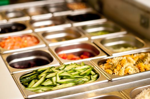 Assortment of food in trays laid out on a restaurant counter-top.