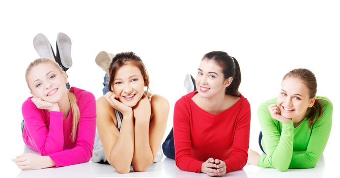 Front view of happy smiling teen girls lying on her tummy on white background