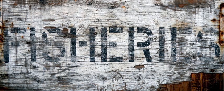 A Grungy, Weathered Sign At A Dock Saying Fisheries