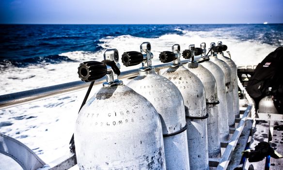 Line of air tanks and breathing apparatus on a dive boat standing against the rail as it heads out to the Great Barrier Reef