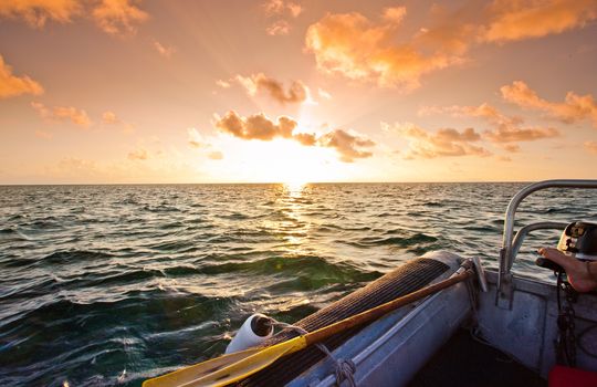 Spectacular orange sunset over the ocean viewed from a rigid inflatable in mid ocean