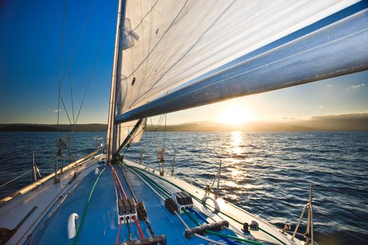 View from the deck of a yacht sailing on the ocean of the sun sinking below the horizon at sunset