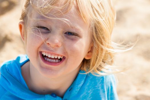 Close-up portrait of a cute laughing boy playing  outdoors