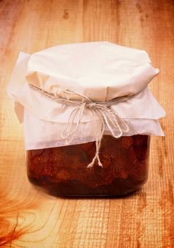 Wild Strawberry Jam Jar Covered with Butter-paper isolated on Wooden background