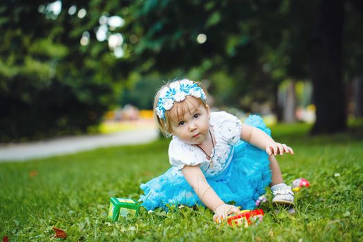 Baby with toys sitting on the green grass