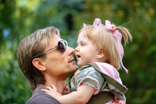 Father holds daughter on hands laughing