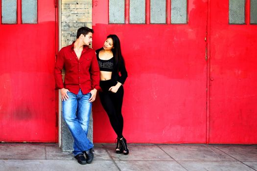 Young couple in front of red fire station doors.