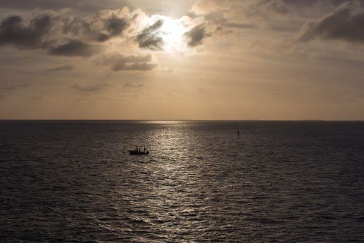 The Sun is setting over a solitary fishing boat on the Gulf of Mexico. This image was taken from the historic Seven Mile Bridge at Marathon Key in the Florida Keys.