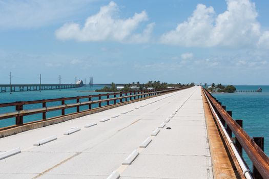 This bridge was built by Henry Flagler as part of the Overseas Railroad to Key West. In the 1935 Labor Day Hurricane the railroad suffered much damage. This bridge was taken over by the state of Florida and converted to part of the Overseas Highway. It has since been replaced by a modern bridge and a 2.2 mile section is now used by walkers and bicyclists for exercise and to get to Pigeon Key. In the photo you can see the old railroad rails are used as handrails.