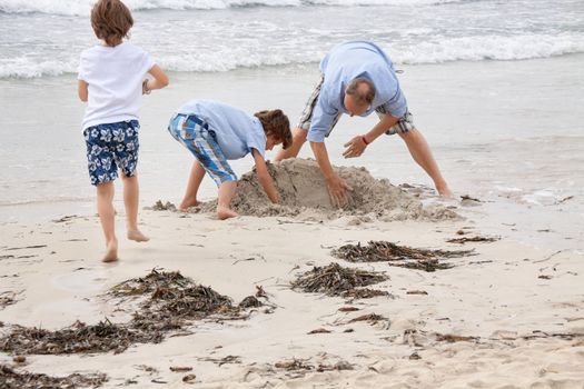 father and sons on the beach playing in the sand holiday family 