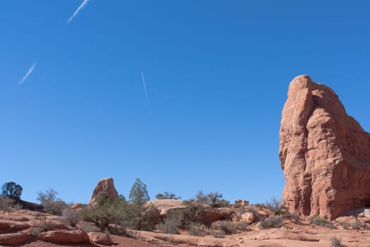 The ancient landscape of Arches National Park contrasts with the contrail of modern aircraft.