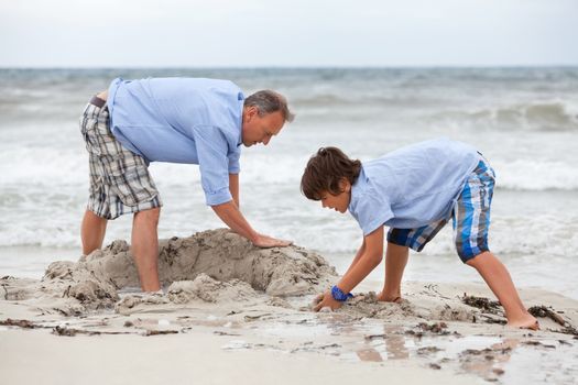 father and sons on the beach playing in the sand holiday family 