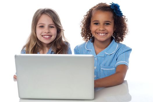 Smiling school girls using laptop together