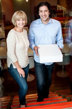 Couple posing on staircase with pizza boxes