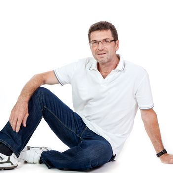 attractive healthy adult man sitting on floor with glasses and jeans t-shirt casual lifestyle isolated