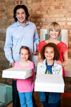 Young girls with parents holding pizza boxes
