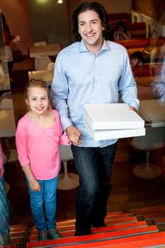 Father holding daughters hand and pizza boxes