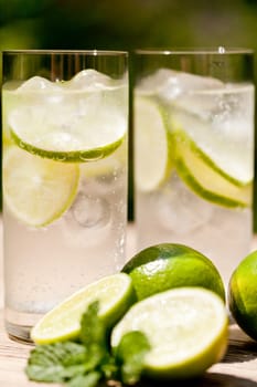 fresh cold refreshment drink mineral water soda with lime and mint on wooden table in summer