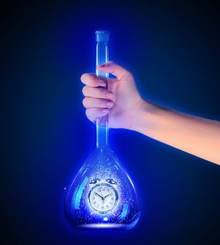 Human hand holding test tube with alarm clock inside